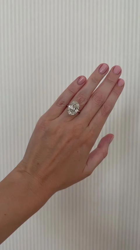 Vertical video of a hand wearing oval diamond engagement ring on striped wall 스톡 동영상 314832938