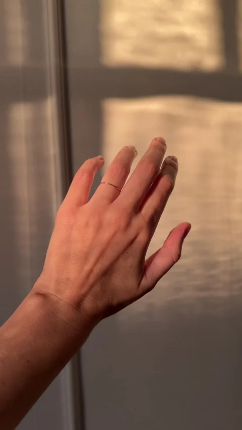Vertical video of a hand wearing a thin gold ring in warm golden hour sunlight Video stock 314621774