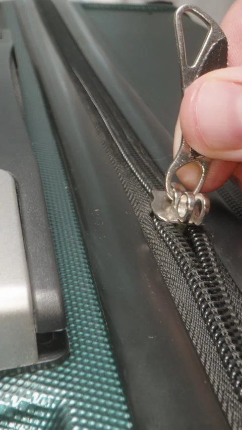 Vertical video. A Hand zips up the suitcase and secures the zipper pulls in the Stock Footage 282300168
