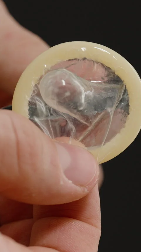 Vertical video. Hands Holding a Condom and Carefully Removing It from Its Stock Footage 301023806