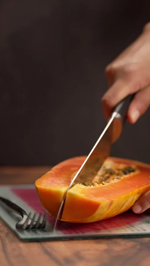 Vertical video, the hands of a latian woman slice a piece of papaya Stock Footage 328896653