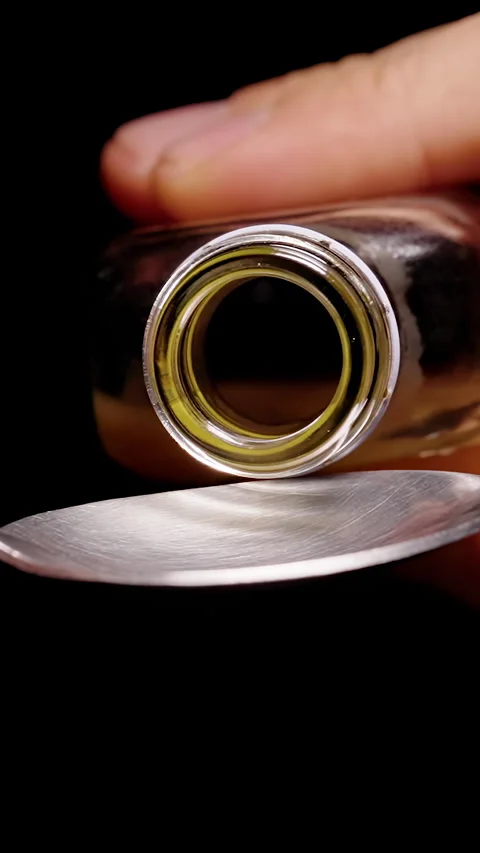 Vertical video. Hands Pour Thick Brown Liquid From a Glass Bottle Into a Metal S Stock Footage 341983194