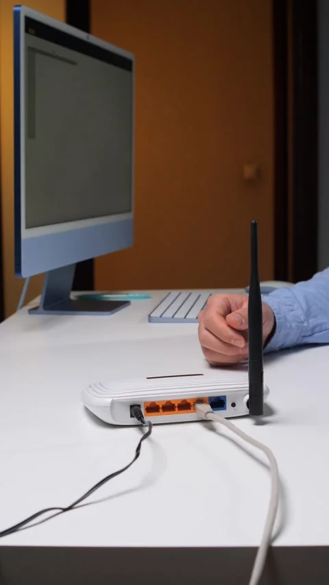 Vertical video hands setting up a wireless router at an office desk, connecting Stock Footage 348447220