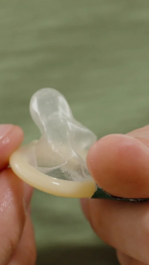 Vertical video. Hands Unrolling a Condom Slightly While Preparing It for Use, Stock Footage 301026731