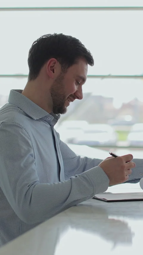 Vertical video Handsome man buying a new car and signing the contract Stock Footage 337239194