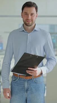 Vertical video Handsome man manager at a car dealership in a business suit ho Fotos Stock