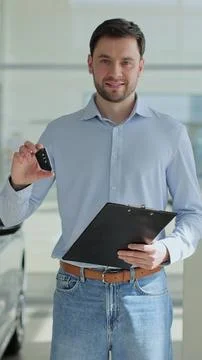 Vertical video Handsome man manager at a car dealership in a business suit ho Fotos Stock