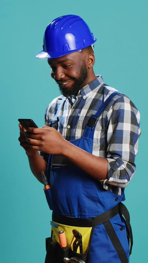 Vertical video: Happy construction worker using smartphone on camera Stock Footage 233667686