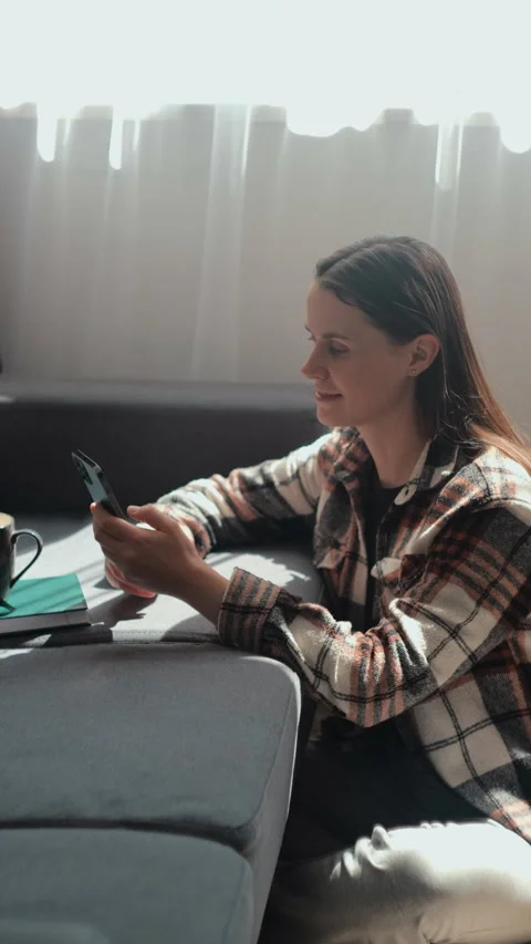 Vertical video of happy cute young woman use cellphone seated on couch Stock Footage 274708763