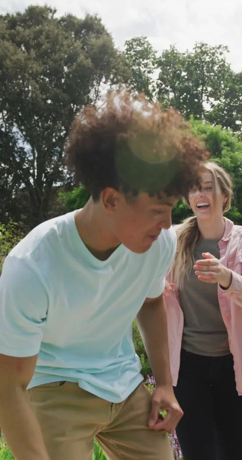 Vertical video of happy diverse couple playing in garden on sunny day Stock Footage 346720880