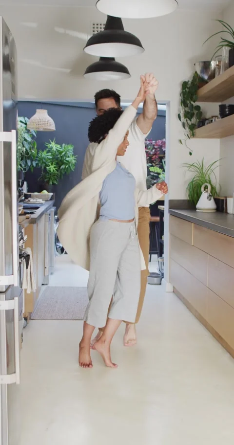 Vertical video of happy diverse couple having fun dancing together in kitchen Stock Footage 346720918