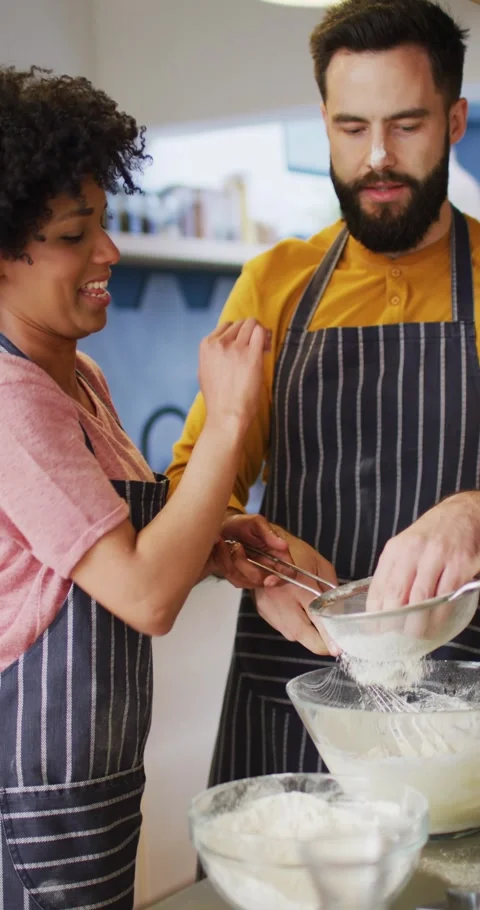 Vertical video of happy diverse couple baking in kitchen, having fun with flour, Stock Footage 346723325