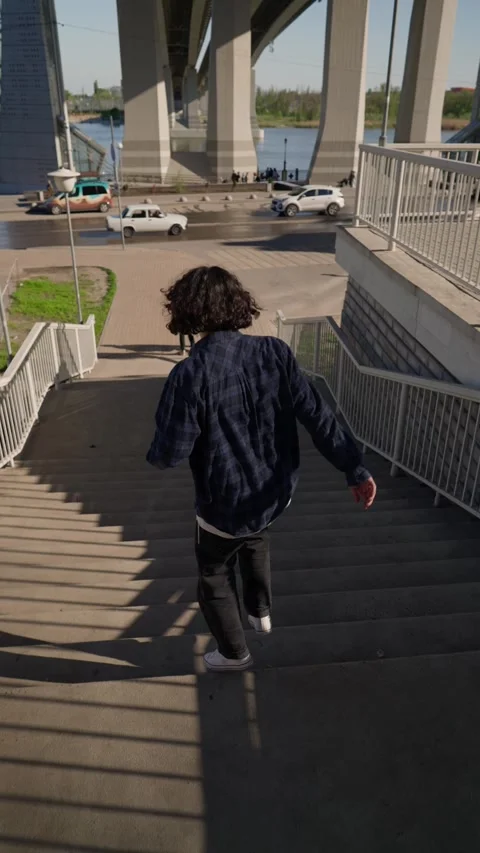 Vertical Video, Happy Man Goes Down Long Staircase Jumping and Rejoicing Success Stock Footage 240955476