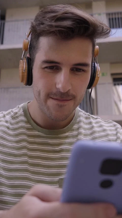 Vertical video of a happy man using a cell phone and looking camera on college Stock Footage 236574572