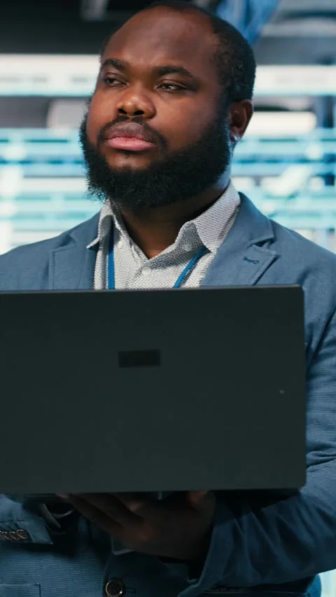 Vertical video Happy programmer in server hub using laptop to do maintenance Stock Footage 330027779