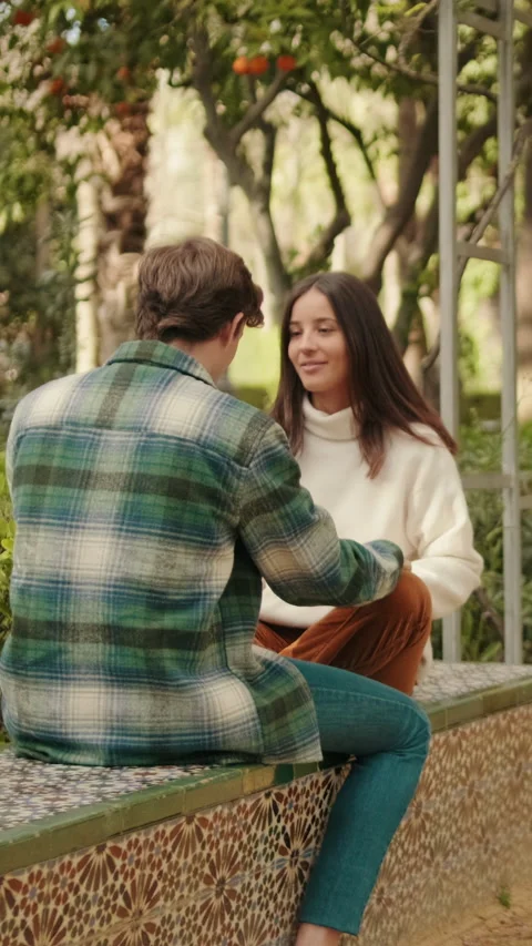 Vertical video, Happy young couple man and woman talking sitting in park Stock Footage 298629521