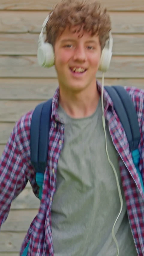 Vertical video. Happy young curly teenager dancing with headphones outdoor, fun Stock Footage 314655477