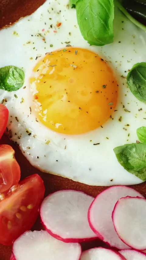 Vertical video. Healthy breakfast. Vegetables and fried egg garnished with .. Stock Footage 340333653