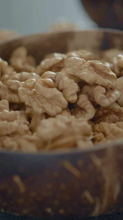 Vertical video Healthy walnut kernels in a rustic bowl on a wooden table Stock Footage 329617552