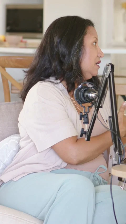 Vertical video: Hearing cue, host tapping tablet, using mic on sofa, pausing Stock Footage 348491388