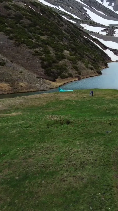 Vertical video: Hikers Group Resting by Alpine Lake and Snowy Peaks Video stock 331991862