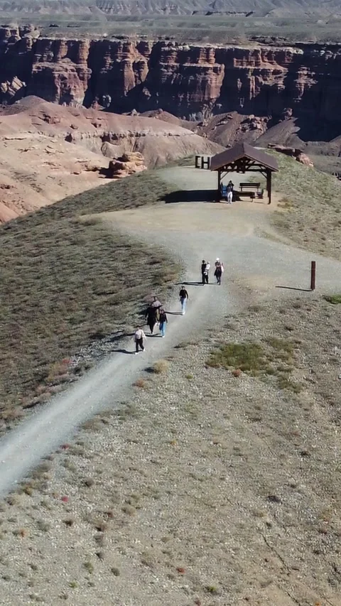 Vertical video: Hikers walking towards gazebo, Martian Charyn Canyon, Kazakhstan Stock Footage 336692772
