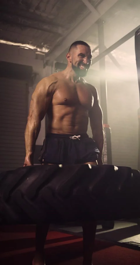 A Vertical Video Of A Hispanic Bodybuilder Exercising, Farmer Tyre Walk In A Gym Stock Footage 158463597