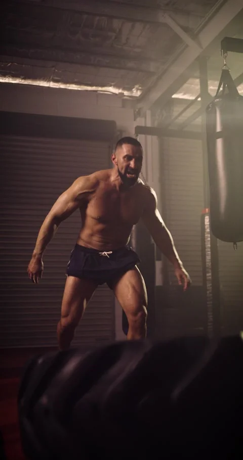 A Vertical Video Of A Hispanic Bodybuilder Tyre Flipping In An MMA Gym Stock Footage 158460462