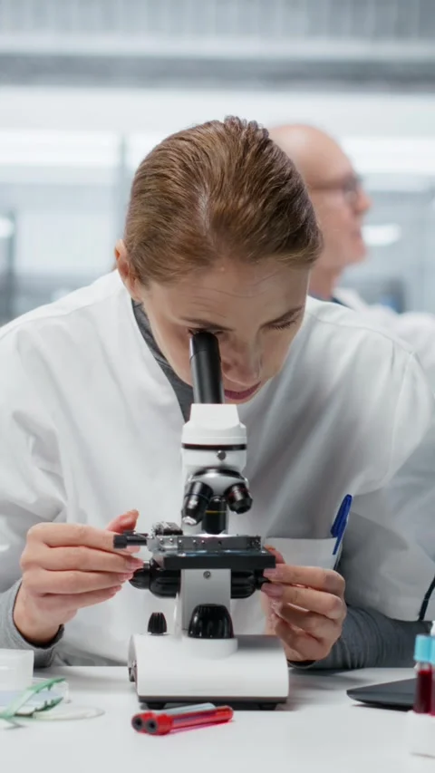 Vertical video Histology technician using compound microscope for detailed Stock Footage 327243836