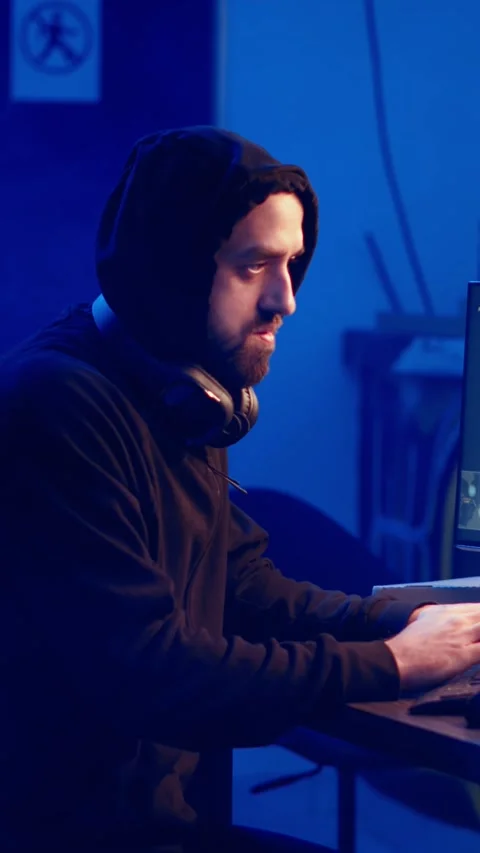 Vertical video Hooded hacker creating pirating crack for software and video game Stock Footage 319517305