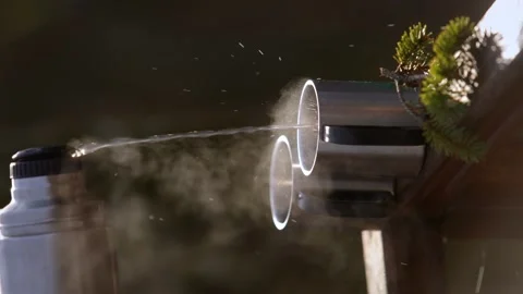 Vertical video. Hot water flows from a metal thermos into two cups. Video stock 264913098