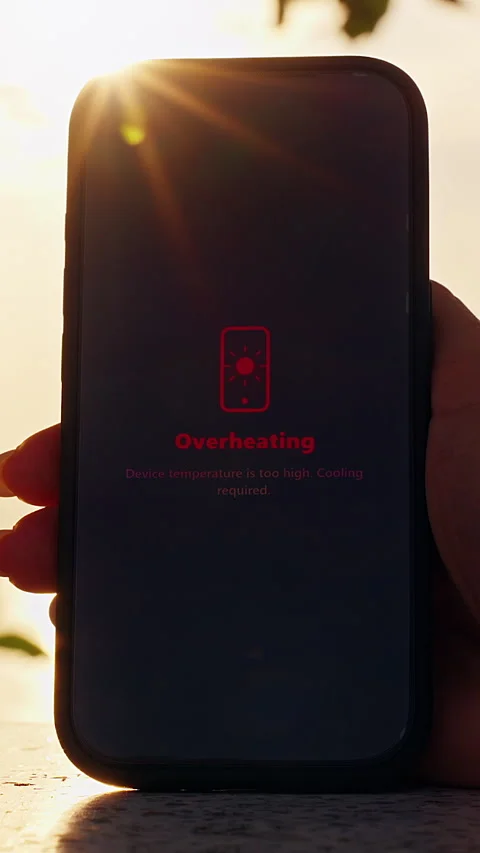 Vertical video. Human Hand Holding Smartphone With Overheating Warning On Screen Stock Footage 330884425