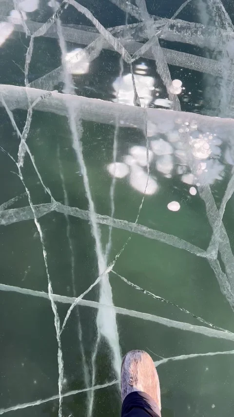 Vertical video of ice texture of Baikal Lake. Tourist in fur boots walks on ice Stock Footage 305425843