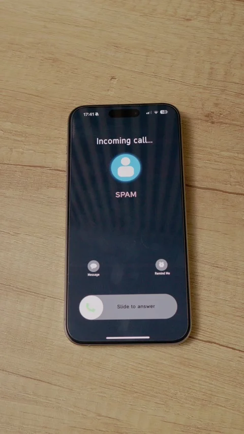 Vertical video Incoming call from spam detected on smartphone placed on a wooden Stock Footage 346715915