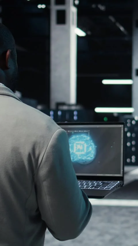 Vertical video IT expert walking in server hub using laptop to enhance AI model Stock Footage 311550362