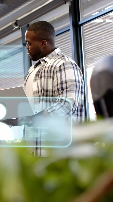 Vertical video: IT pro holding laptop, glancing left and causing AR overlay over Stock Footage 333777159