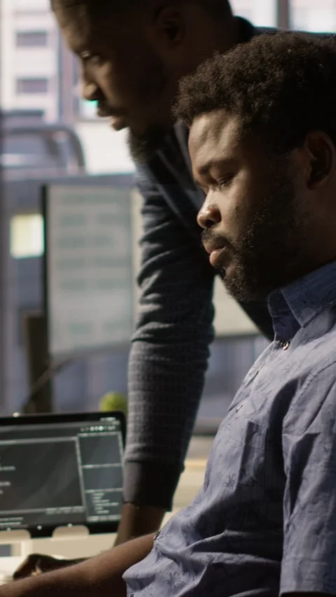 Vertical video IT specialist assisted by coworker to compare data in office Stock Footage 319478636