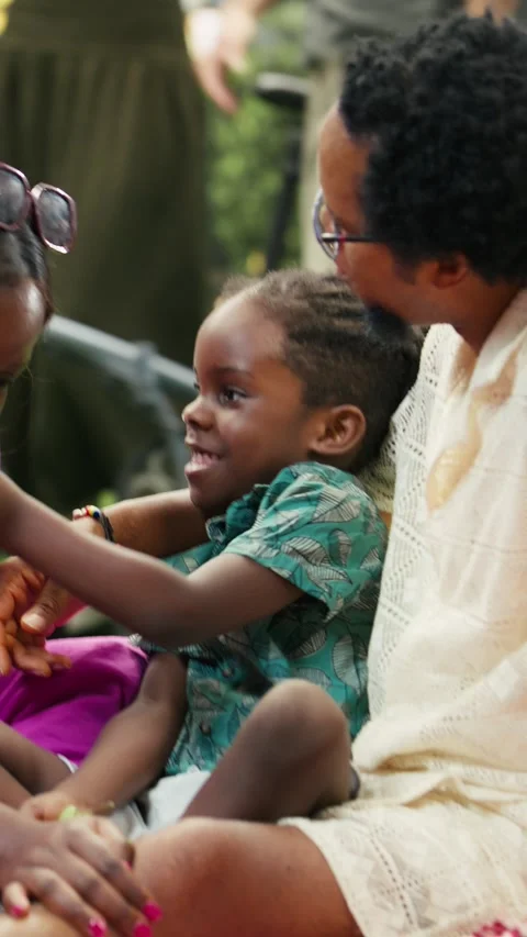 Vertical Video Joyful boy offering grapes to parents relaxing on checkered Stock Footage 341472832