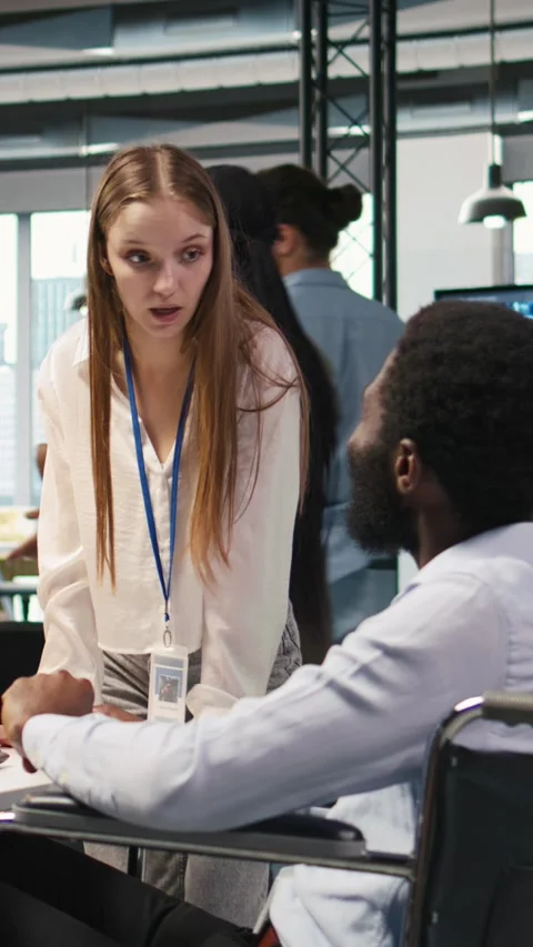 Vertical video Junior dev and coworker in wheelchair developing AI software Stock Footage 312708672
