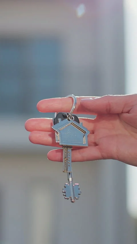 Vertical video Key ring with keychain house in hand on background of house. Stock Footage 338088601