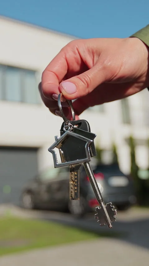 Vertical video Key ring with keychain house in hand on background of house. Stock Footage 338088924