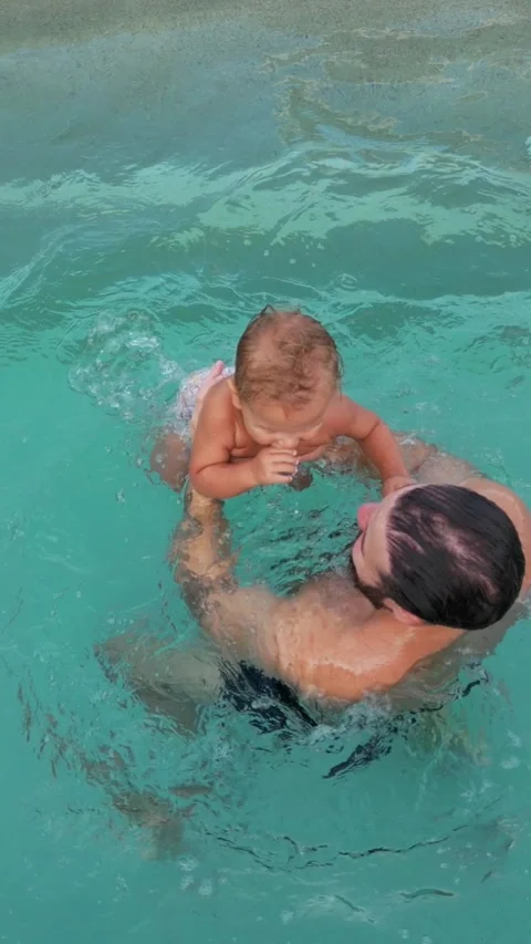 Vertical video. The kid approaches the pool and jumps into the water. Dad Video stock 289521141