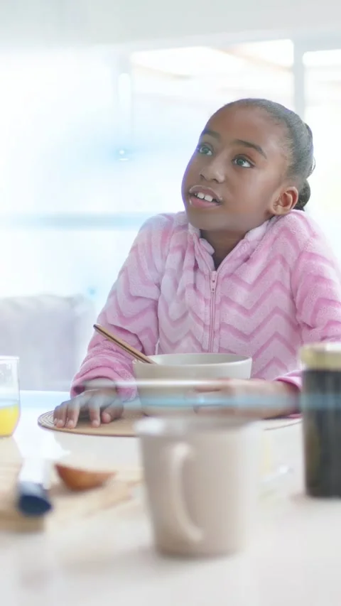 Vertical video: Kid at table hearing adult for health halo spinning across face Stock Footage 333513491