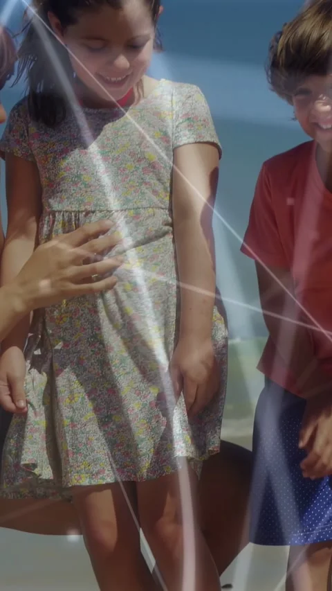 Vertical video: Kids standing on sand adult tapping dress to point at shell Stock Footage 333777264