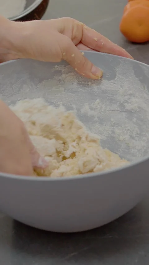 Vertical video Kneading cookie dough with hands in a cozy kitchen setting Stock Footage 329629584