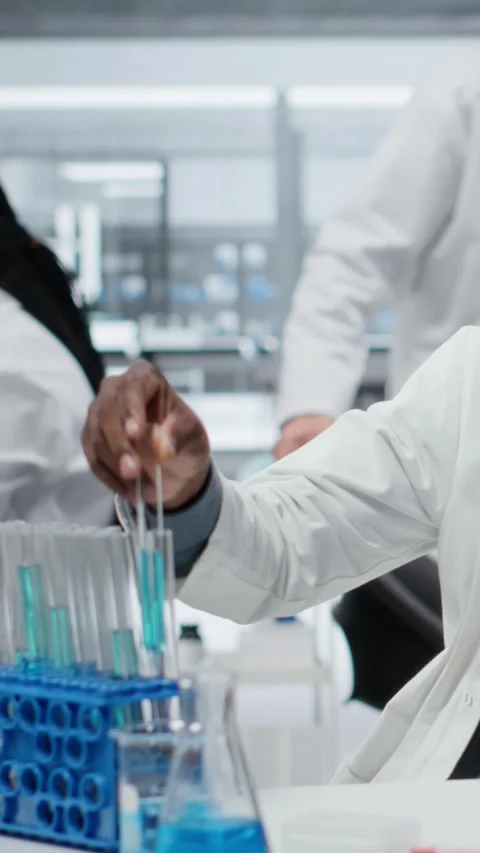 Vertical video Lab expert using laptop to investigate blue liquid polymer Stock Footage 327334566