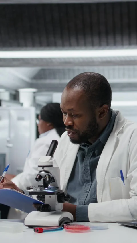 Vertical video Lab researcher looking through scientific microscope lens to Stock Footage 325817899