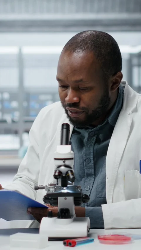 Vertical video Lab researcher looking through scientific microscope lens to Stock Footage 325917278