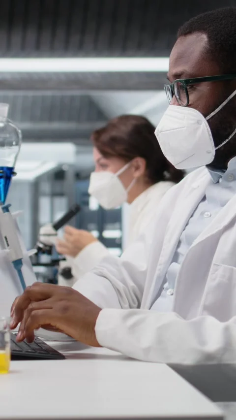 Vertical video Lab scientist removing protective face mask to scratch beard Stock Footage 319722499
