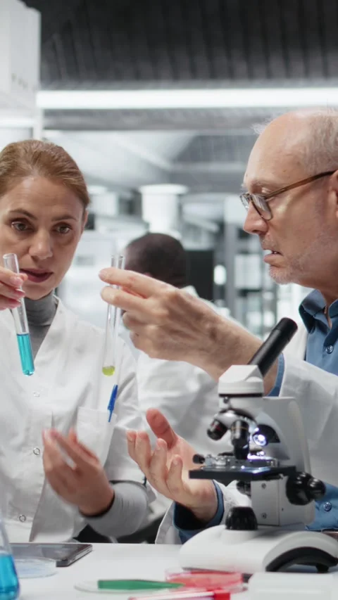 Vertical video Lab team leader teaching intern to analyze liquid polymer Stock Footage 325681167